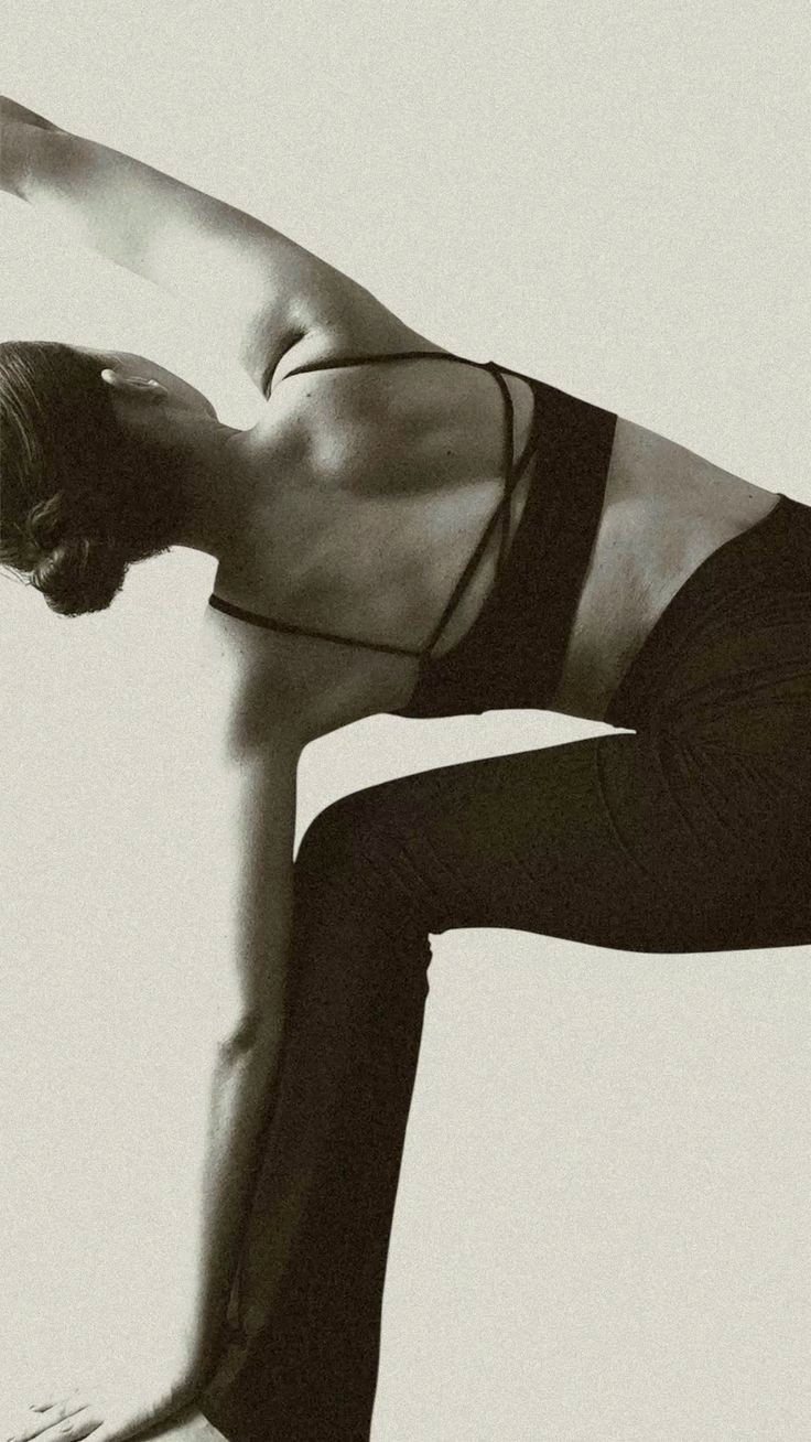 A woman in a deep side stretch, photographed in soft monochrome